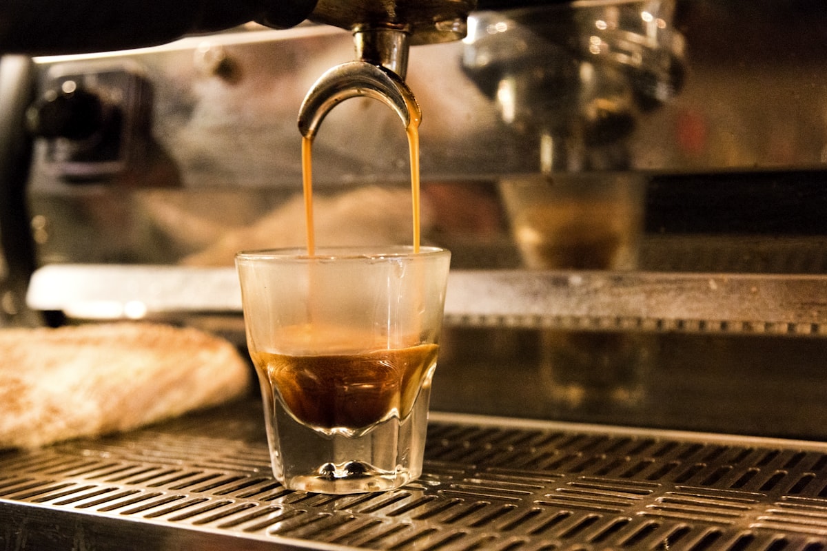 Espresso being pulled, golden crema forming, warm morning light